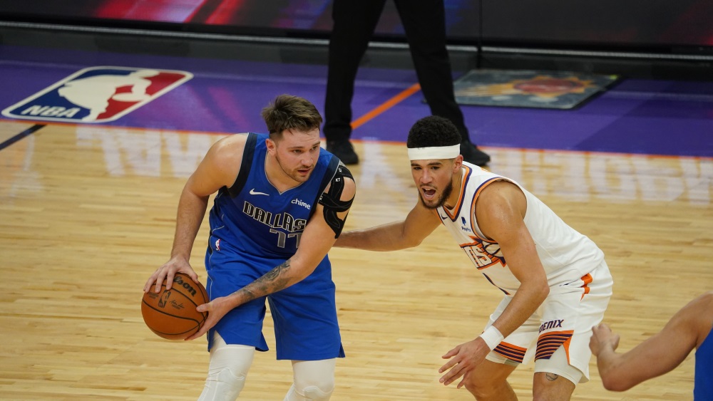 Suns guard Devin Booker defending Mavericks guard Luka Doncic...