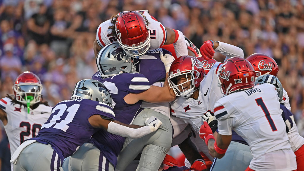Defensive back Genesis Smith #12 of the Arizona Wildcats goes over the top to try and stop quarterb...