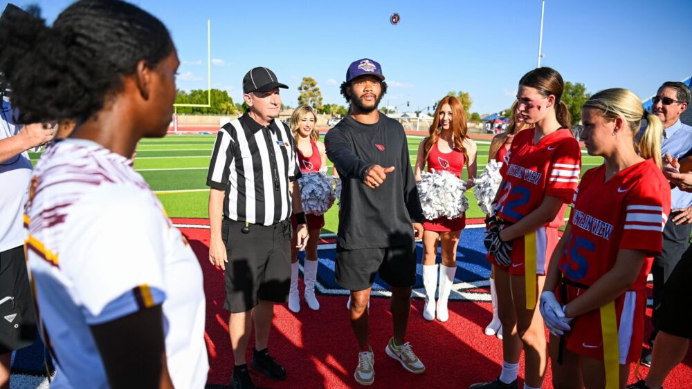 Kyler Murray flips a coin before a girls flag football game in 2023...
