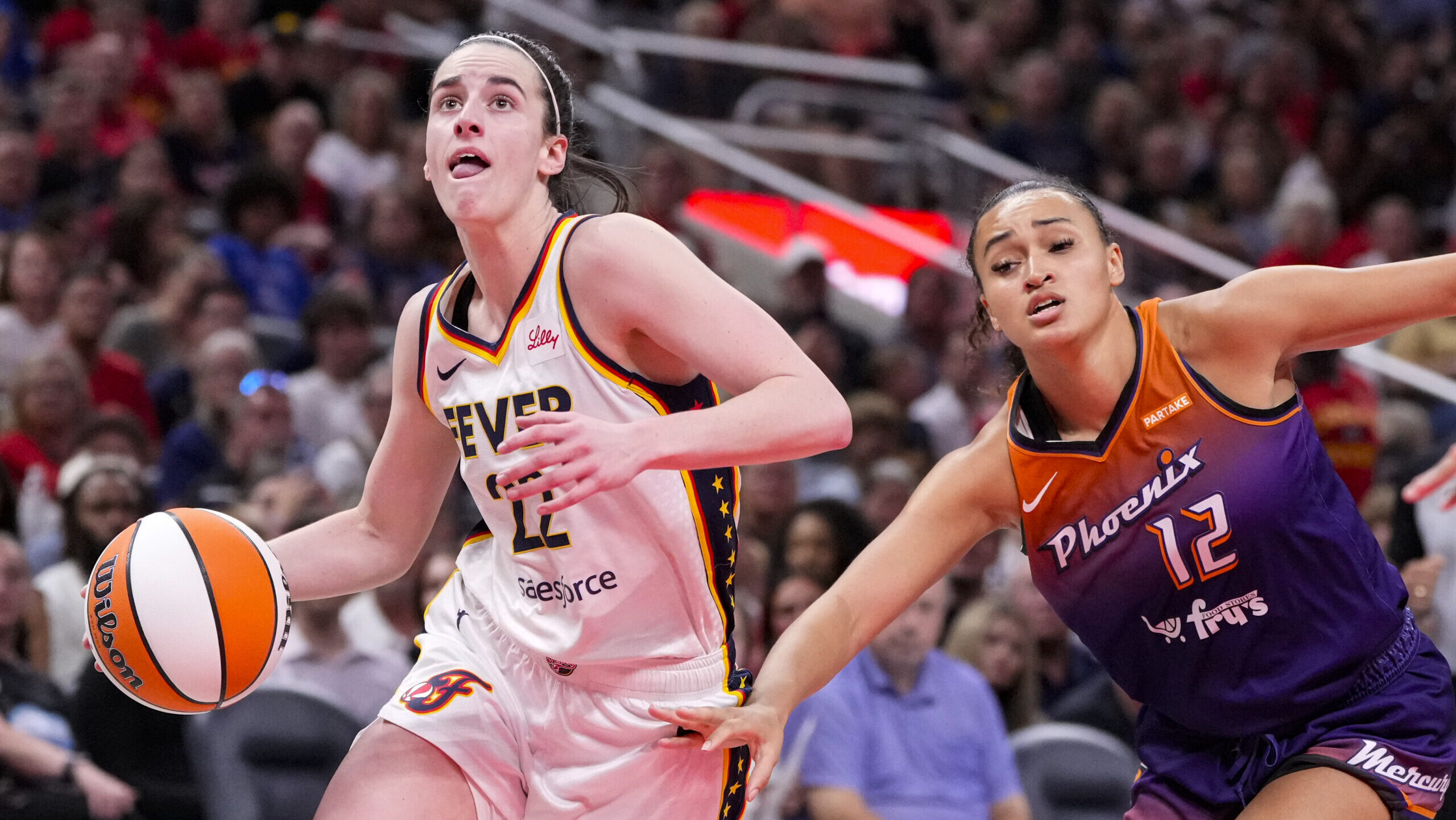 Indiana Fever guard Caitlin Clark (22) drives past Phoenix Mercury's Celeste Taylor (12) in the sec...