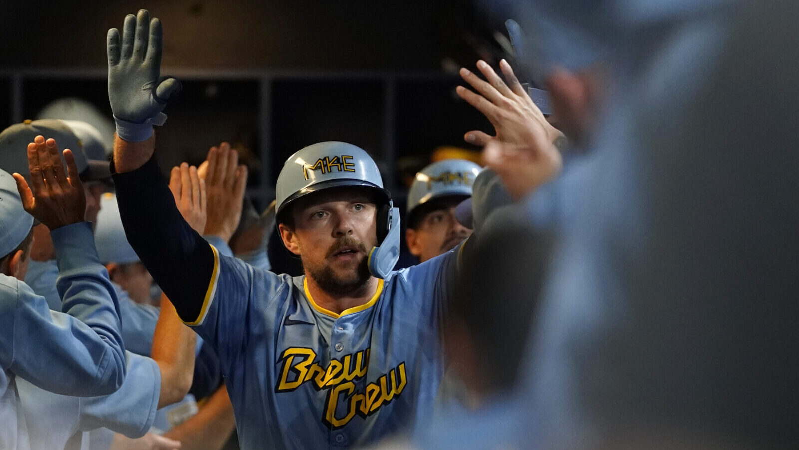 Brewers first baseman Rhys Hoskins high-fives teammates in dugout after hitting a grand slam...
