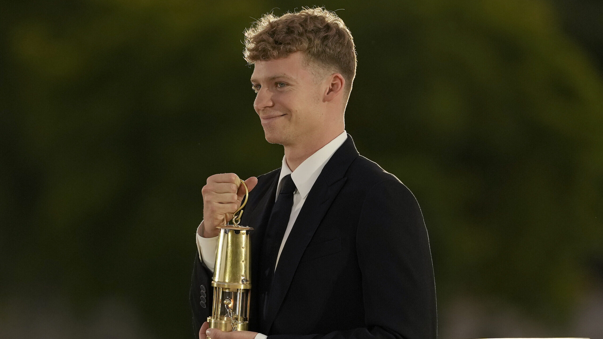 French swimmer Leon Marchand carries a lantern containing the Olympic flame in the Tuileries garden...